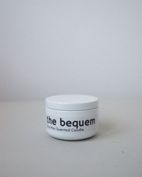 White metal tin travel candle by The Bequem with printed label, minimalist background