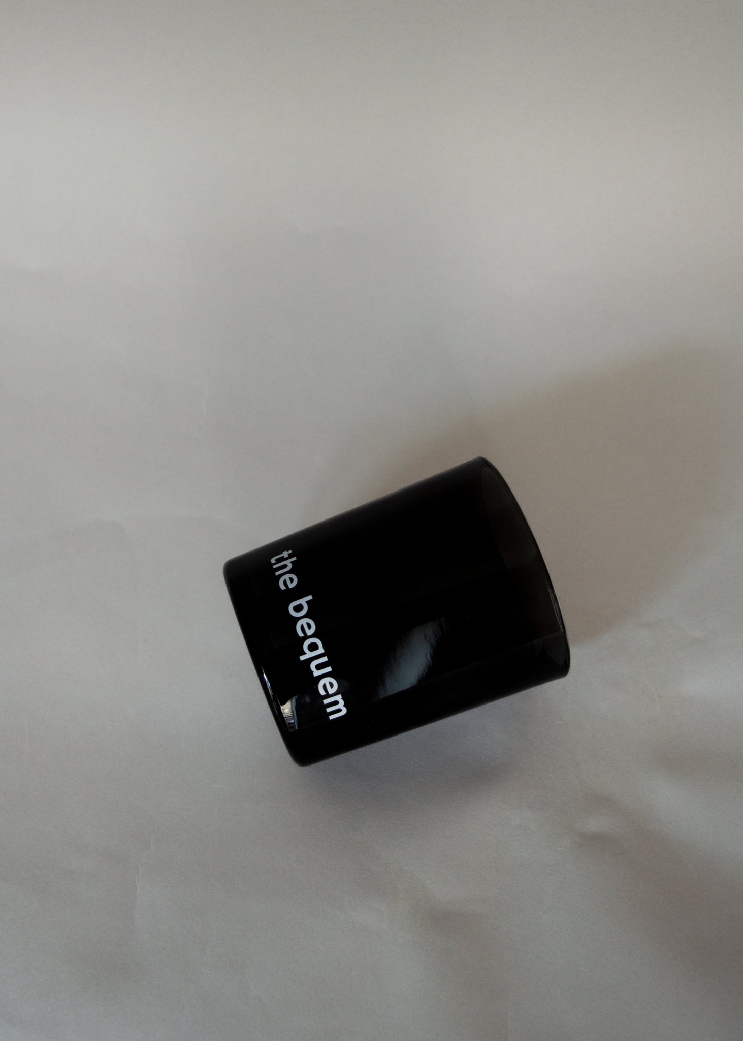 Black candle glass with 'the bequem' branding on a white background