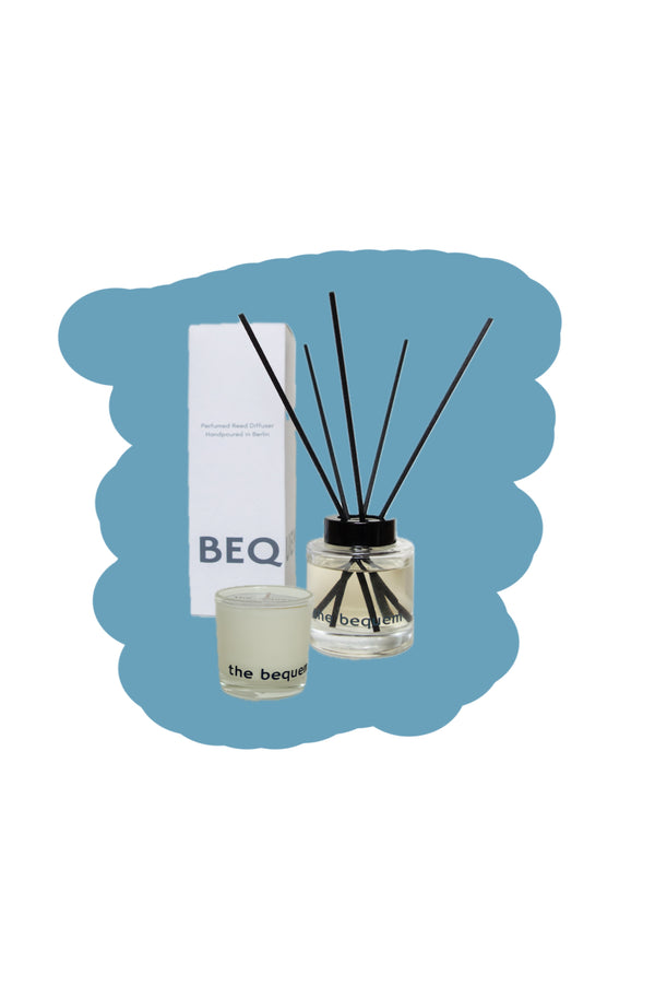 The Bequem small candle and reed diffuser gift set with minimalist white box and black reeds on a soft blue background