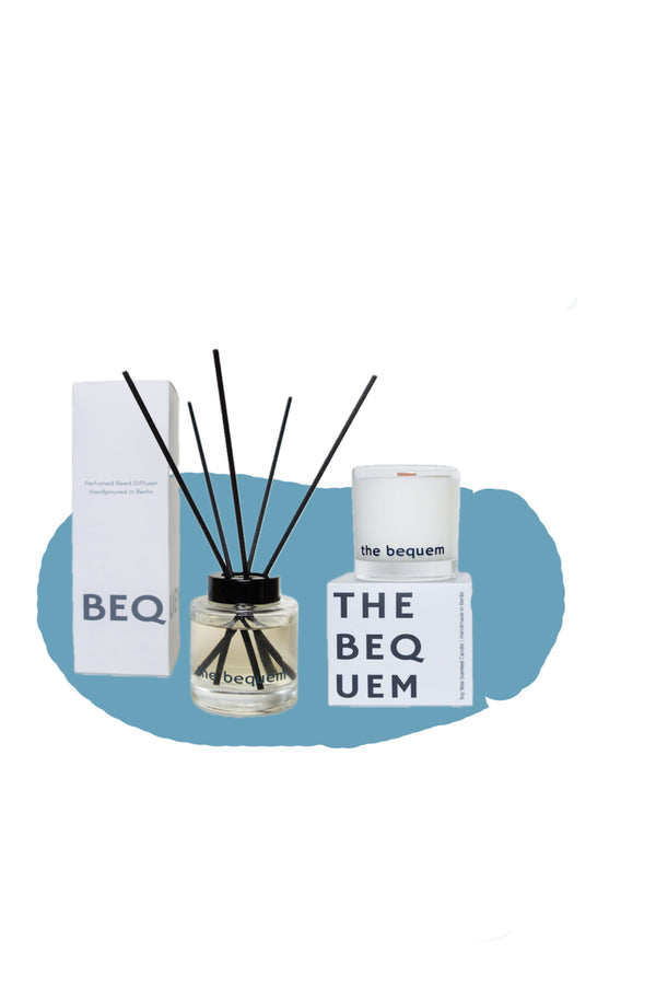 The Bequem classic home fragrance set featuring a soy wax candle with wooden wick and a clear glass reed diffuser with black reeds, displayed with minimalist white packaging on a blue background